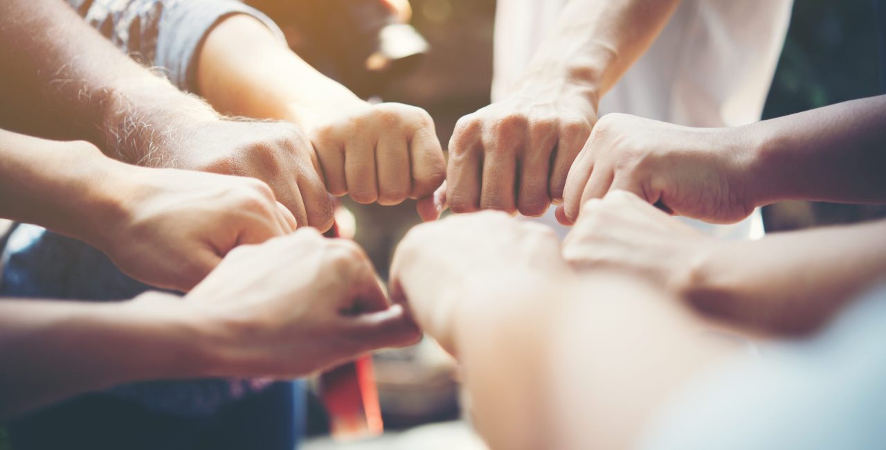 Close up of young people putting their hands together. Team with stack of hands showing unity and teamwork.